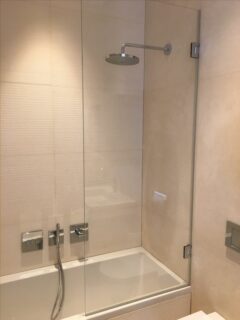 Custom made glass shower screen over bath with hinge